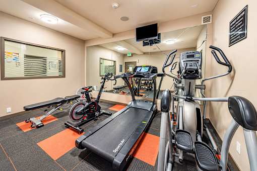 A gym with treadmills, exercise bikes, and a television.