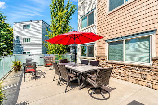 A patio with a table and chairs and an umbrella.