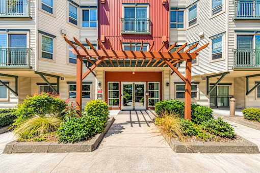 A building with a red door and a wooden pergola in front.