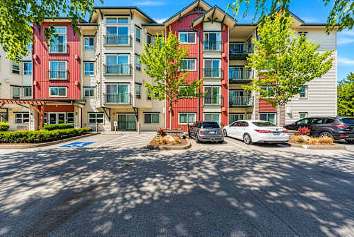 A multi-story apartment building with cars parked in front.