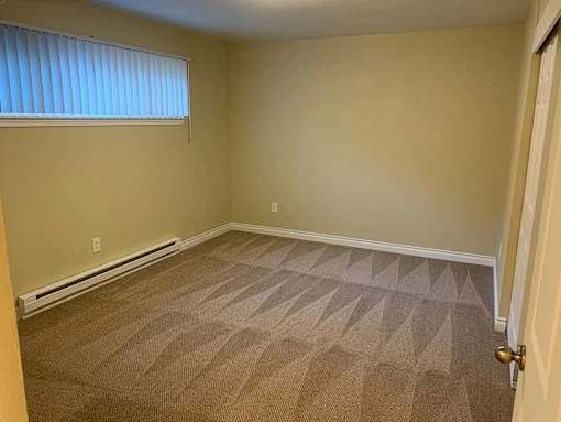 A room with a carpeted floor and a door on the right side.
