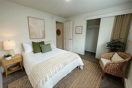 A bedroom with a bed, chair, and painting.