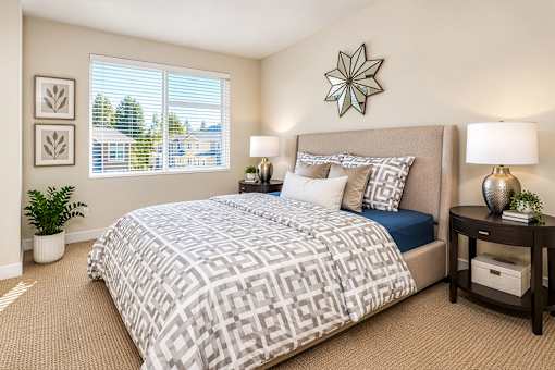 A bedroom with a large bed and a window with blinds.
