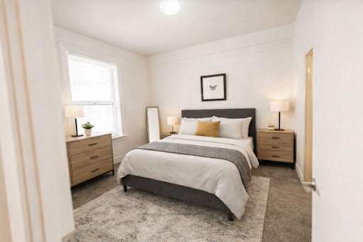 A bedroom with a large bed, two nightstands, and a window.