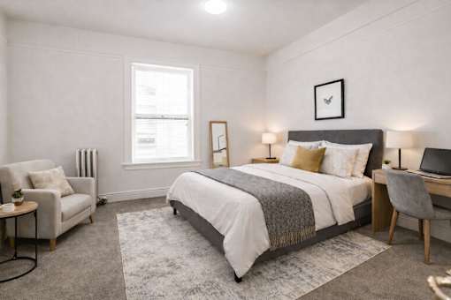 A bedroom with a large bed, a chair, and a desk.