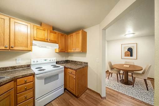 A kitchen with a white stove top oven and wooden cabinets.