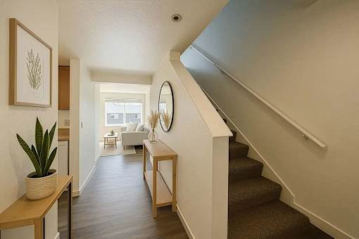A hallway with a staircase and a mirror on the wall.