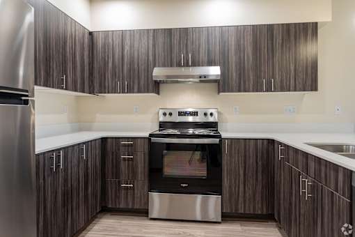 A modern kitchen with dark wood cabinets and stainless steel appliances.