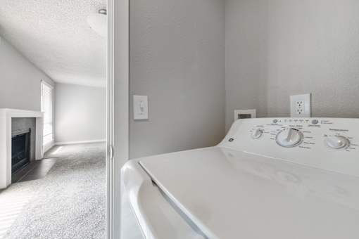 A white washing machine in a room with a fireplace.