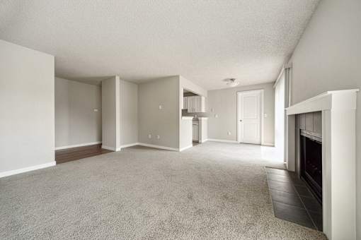 A spacious living room with a fireplace and carpeted floor.