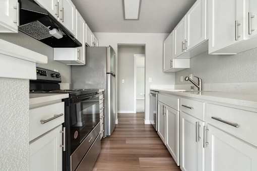 A kitchen with white cabinets and black appliances.
