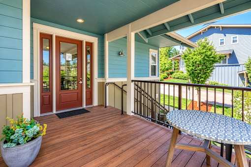 A blue house with a wooden deck and a table.