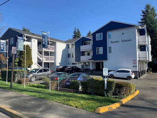 A Burien Manor apartment complex with a parking lot in front.