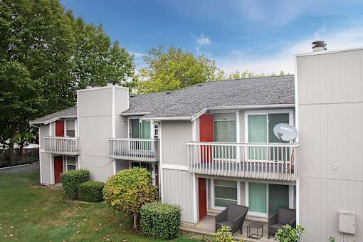 A small white house with a red door and a balcony.