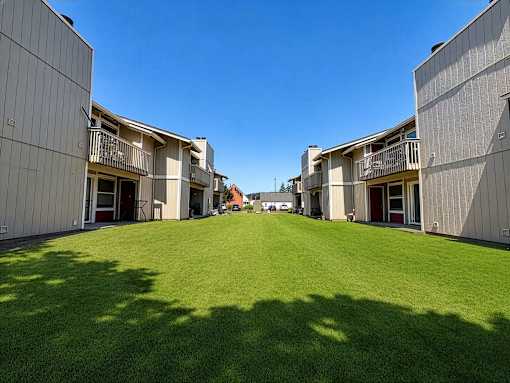 A sunny day at the apartment complex with green lawns and buildings on either side.