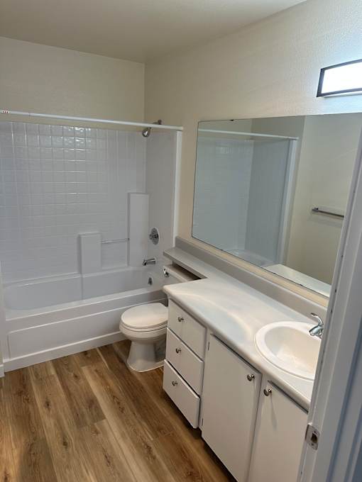 A white bathroom with a toilet, sink, and mirror.