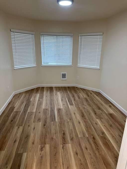 A room with wooden flooring and white walls.