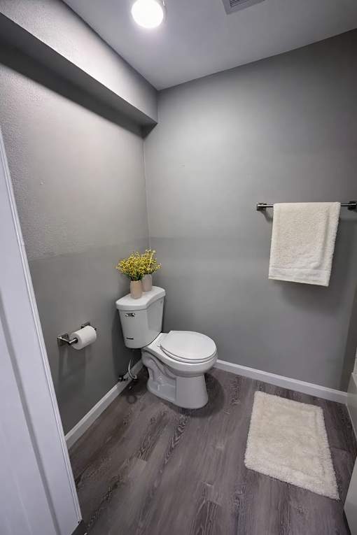 A small bathroom with a toilet, a flower pot, and a towel.