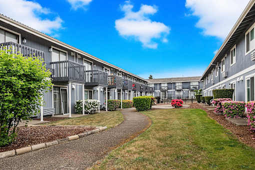 A row of grey apartment buildings with a walkway in the middle.