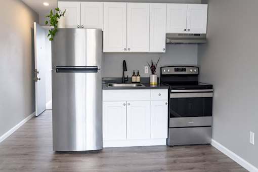 A modern kitchen with a stainless steel refrigerator and white cabinets.