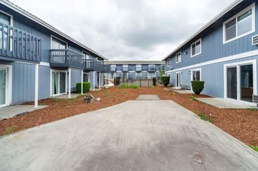 A long concrete driveway leads between two rows of identical houses.