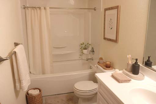 A white bathroom with a towel hanging on the towel rack.