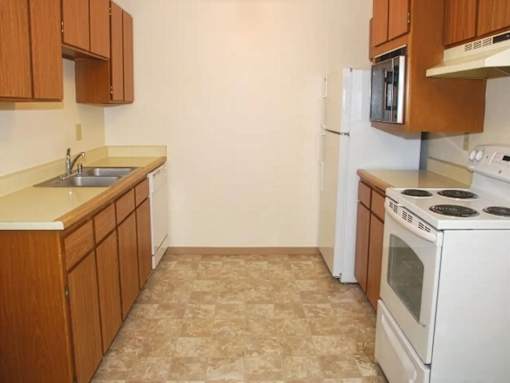 A kitchen with white appliances and wooden cabinets.