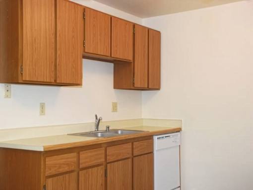 A kitchen with wooden cabinets and a white dishwasher.