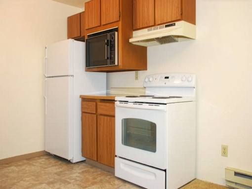 A white refrigerator and oven in a kitchen with brown cabinets.