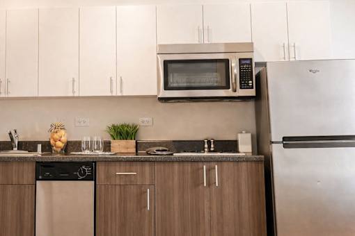 A kitchen with a stainless steel refrigerator and a microwave above the stove.