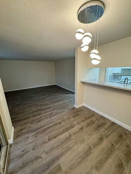 A room with wooden flooring and a circular light fixture hanging from the ceiling.