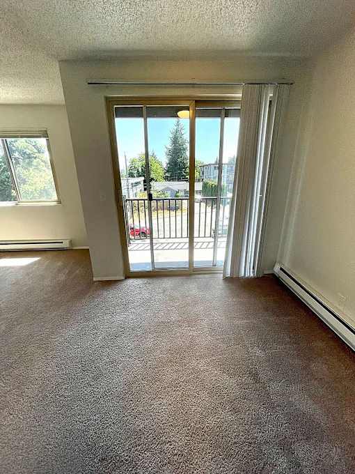 A room with a carpeted floor and a sliding glass door leading to a balcony.
