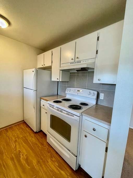 A kitchen with a white stove and refrigerator.