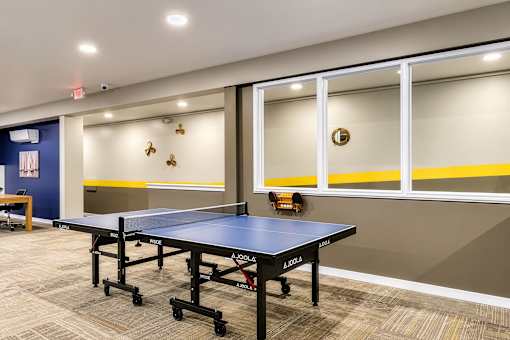 A room with a blue and yellow wall and a ping pong table.