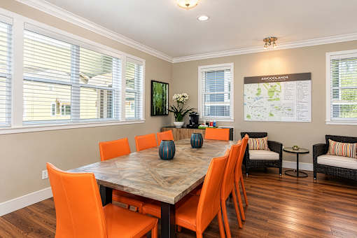 A dining room with a wooden table and orange chairs.
