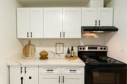 A kitchen with white cabinets and a black stove top oven.