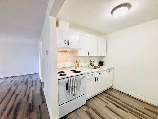 A kitchen with white cabinets and a wooden floor.