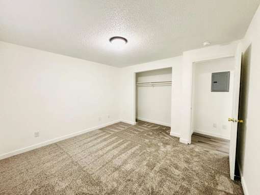 A room with a carpeted floor and a door on the right side.