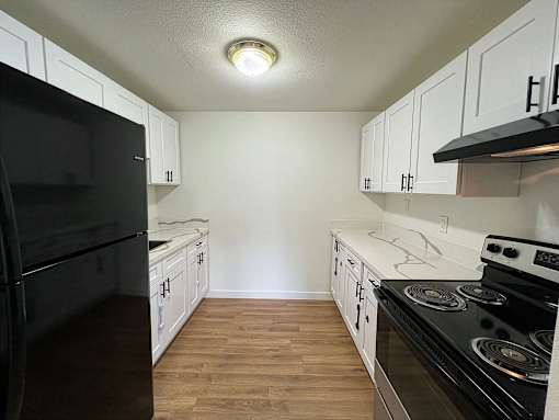 A kitchen with black appliances and white cabinets.