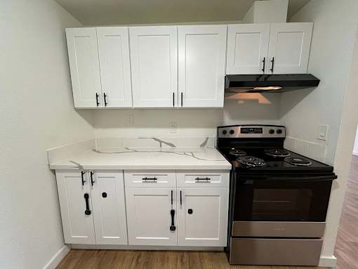 A kitchen with white cabinets and a black stove top oven.