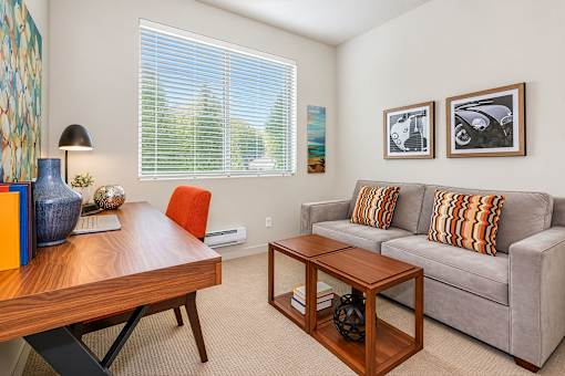 A living room with a grey couch, a wooden coffee table, and a table with a lamp and vases.
