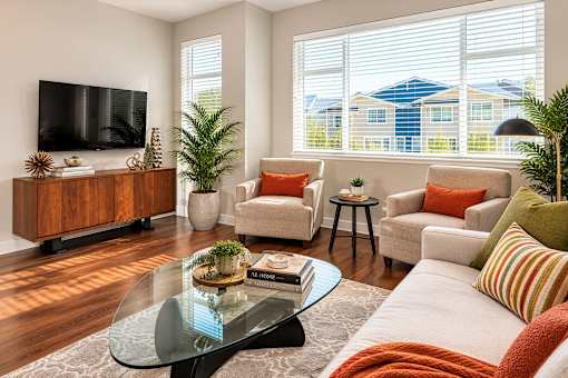 A living room with a glass coffee table and a flat screen TV on the wall.