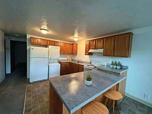 A kitchen with a white refrigerator, wooden cabinets, and a granite countertop.