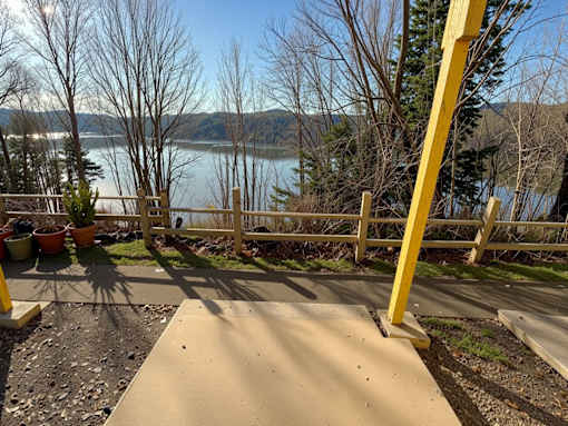 A yellow railing is in the foreground of a view of a lake.