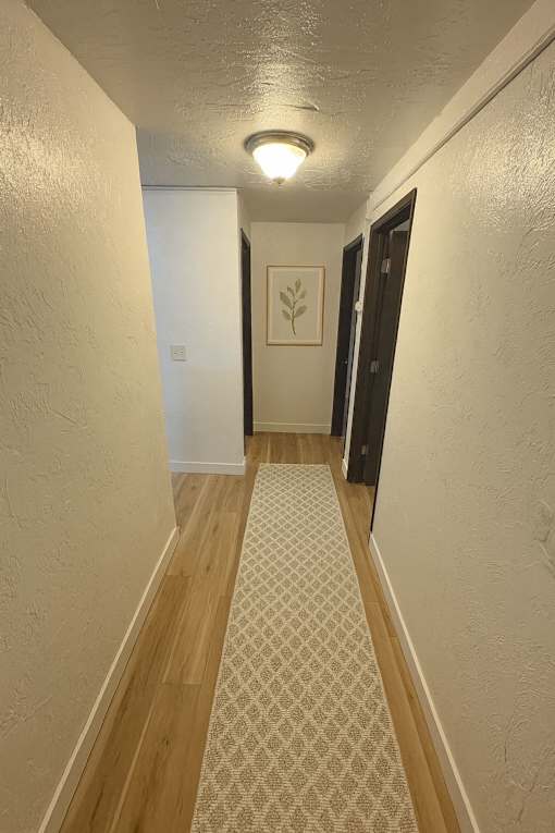 A hallway with a light on the ceiling and a patterned carpet on the floor.