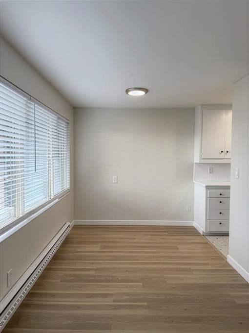 A room with wooden floors and a window with blinds.
