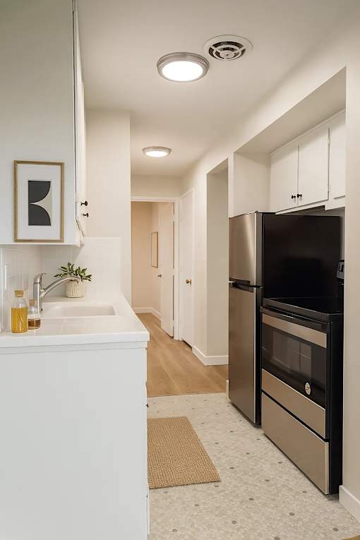 A kitchen with a black fridge and white cabinets.