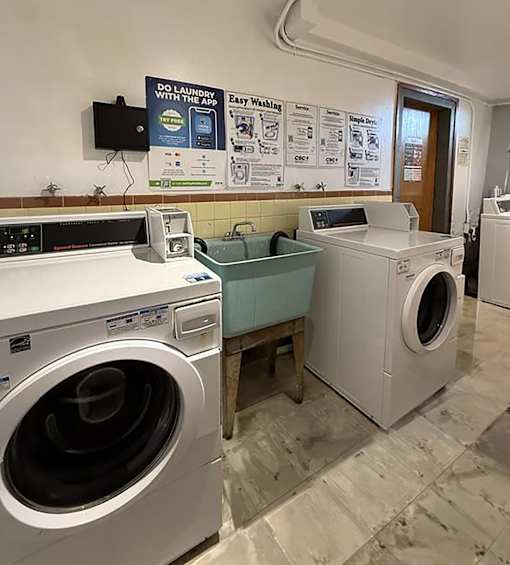 A laundromat with a sign that says "Do Laundry with the App" and a washer and dryer.