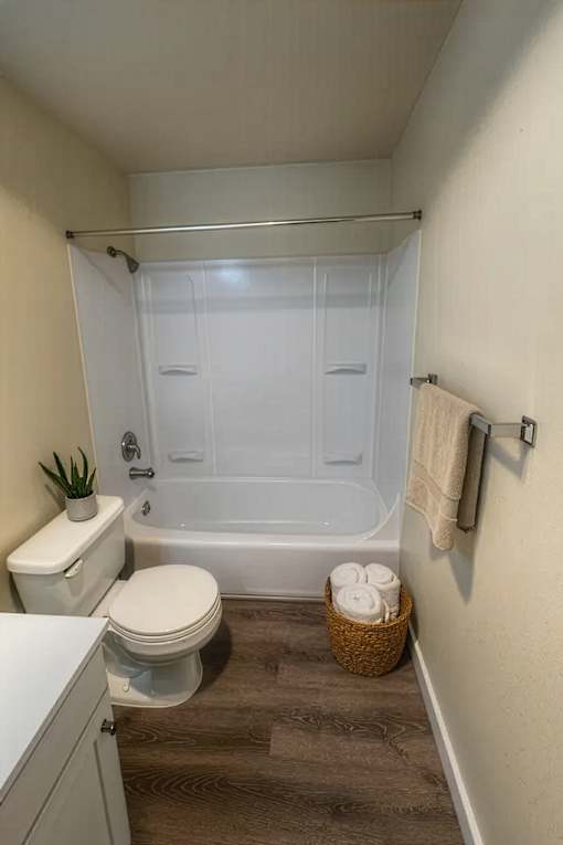 A white toilet sits next to a white bathtub in a small bathroom.