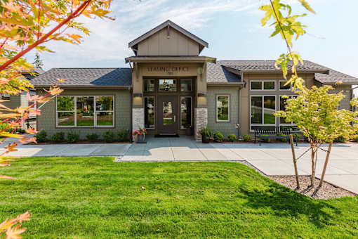 A building with a sign that says "Leasing Office" is surrounded by a grassy area and trees.